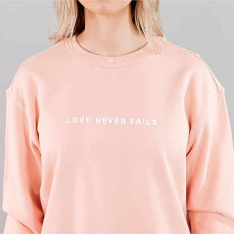 LOVE NEVER FAILS SWEATSHIRT PALE PINK